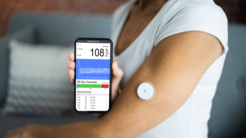 Person with diabetes uses a CGM tracker and phone app to monitor glucose